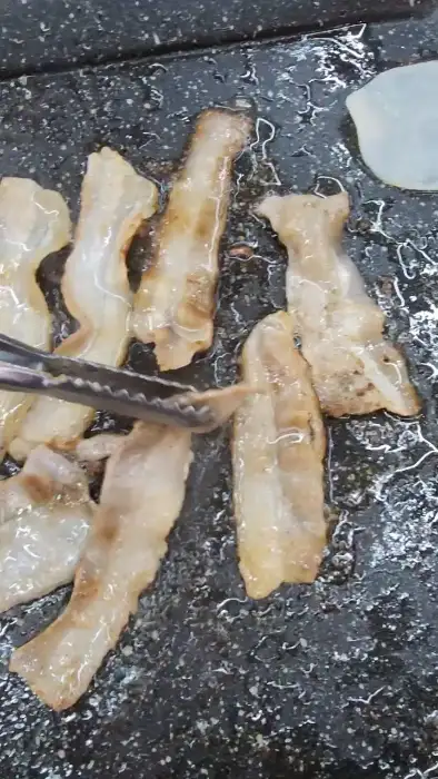 불판 위에서 익어가는 대패삼겹살과 야채들