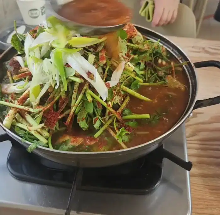 국자로 매운탕을 뜨고 있는 모습. 건더기가 푸짐하게 담겨 있다.