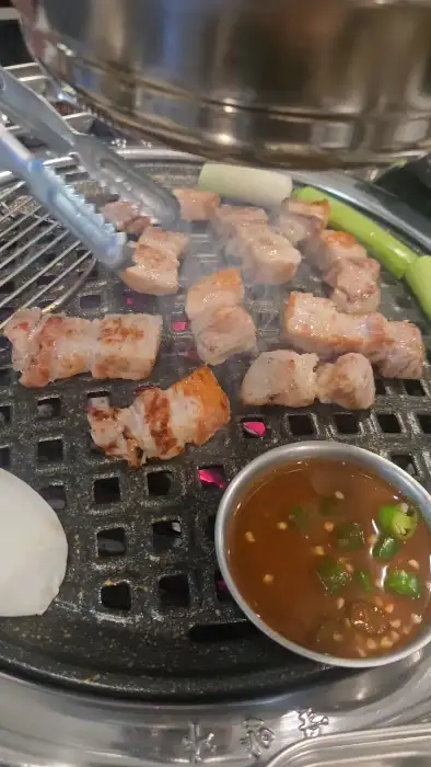 숯불 위에서 익어가는 돼지고기 조각들
