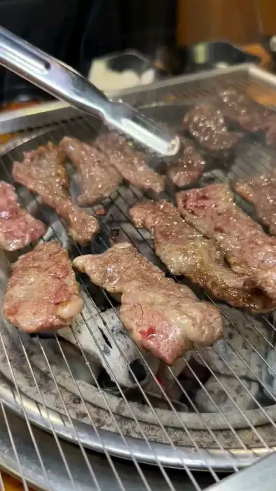집게로 집어 올린 잘 구워진 소갈비살