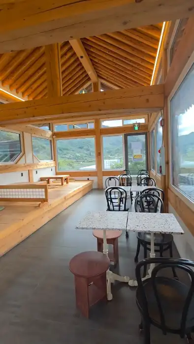 통창 너머로 산과 강이 보이는 카페 내부의 모습. 원목 테이블과 의자가 편안한 분위기를 자아낸다.