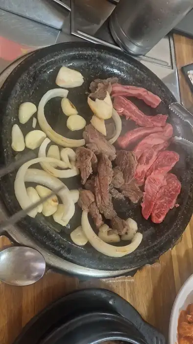 돌판 위에서 익어가고 있는 소고기와 양파, 마늘