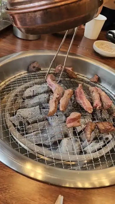 집게로 숯불 위 소갈비살을 뒤집는 모습