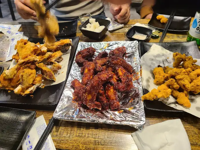 테이블에 놓인 여러 접시의 치킨과 곁들임