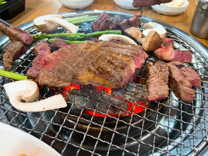 숯불 위에서 맛있게 구워지고 있는 한우와 채소