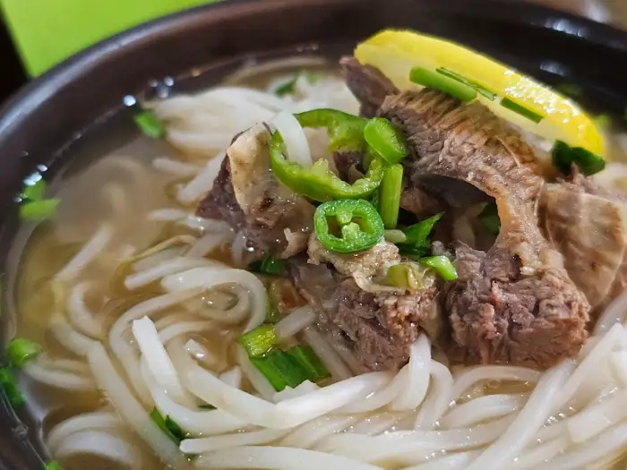 소갈비탕으로 보이는 맑은 국물에 큼직한 고깃덩어리와 면이 담겨 있습니다.