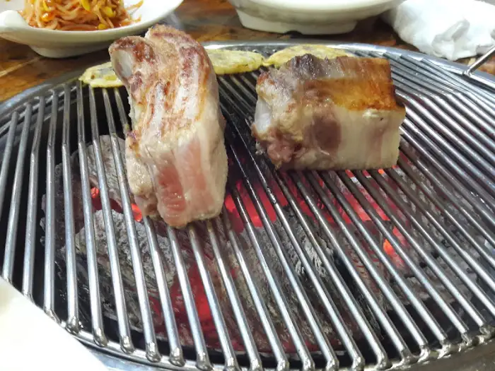 숯불 위에서 구워지고 있는 두툼한 삼겹살 덩어리