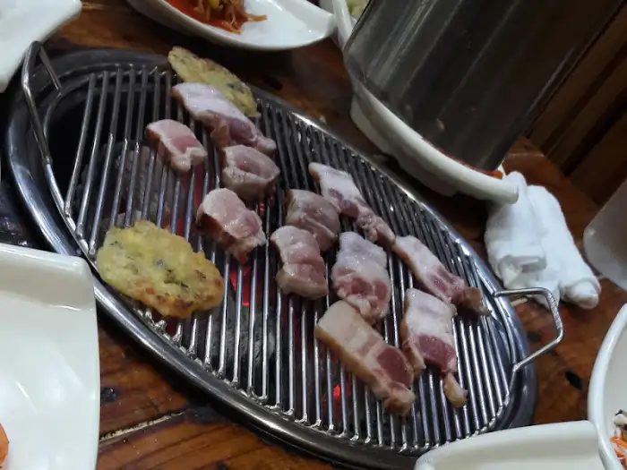 숯불 석쇠 위에서 맛있게 익어가고 있는 돼지고기 조각들