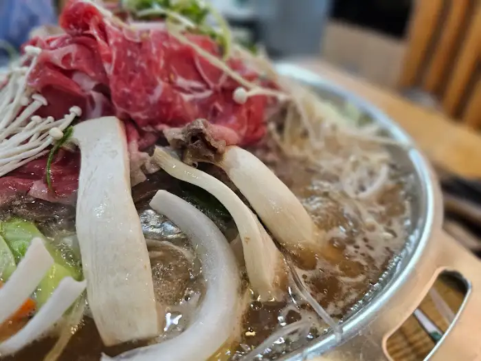 끓고 있는 전골 요리의 모습. 신선한 야채와 고기가 어우러져 맛있어 보입니다.