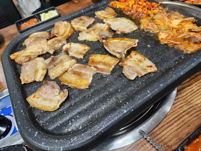 불판 한가득 삼겹살과 김치, 콩나물 등이 함께 익어가는 모습
