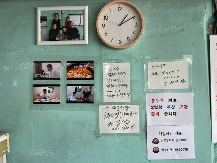 식당 내부 벽에 걸린 가족사진과 시계, 메뉴판 사진.