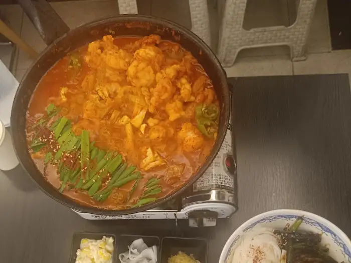 테이블 위에 놓인 곱도리탕, 버너 위에서 지글지글 끓고 있는 모습과 곁들임 찬들이 함께 담겨 있습니다.