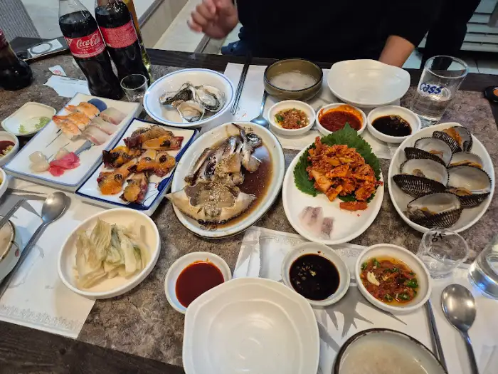 여러 사람이 함께 앉아 식사하는 테이블의 모습. 다양한 해산물 요리와 음료가 준비되어 있다.