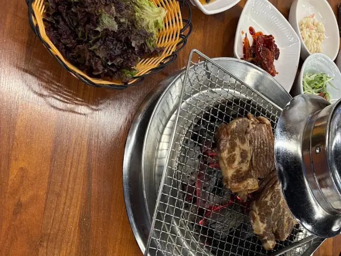 숯불 위에서 노릇하게 구워지고 있는 돼지갈비 모습
