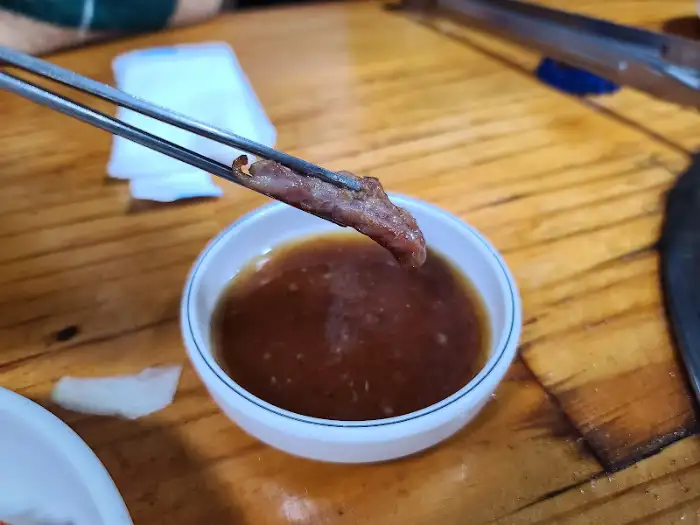 집게로 오리고기 조각을 소스에 찍는 모습