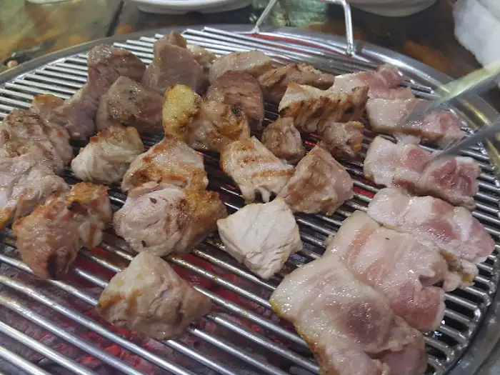숯불 위에서 익어가는 다양한 부위의 돼지고기