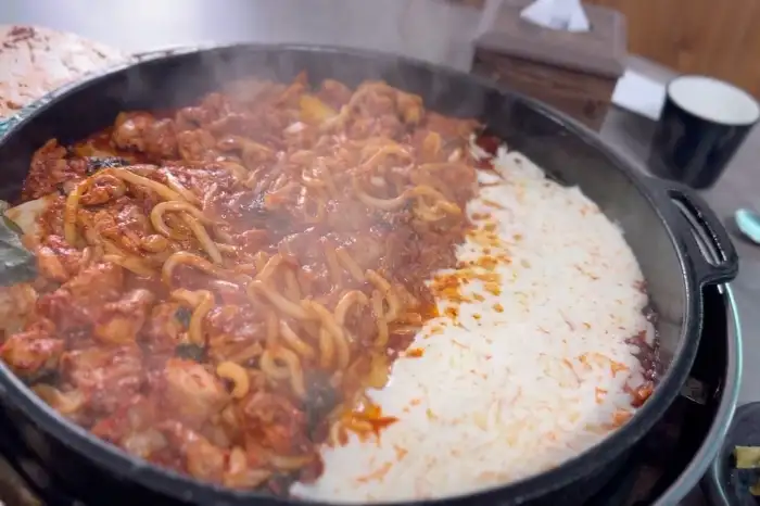 김이 모락모락 나는 닭갈비 철판 위에 치즈가 녹고 있는 모습