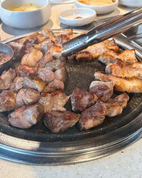 잘 익은 흑돼지를 집게로 집어 올리는 모습