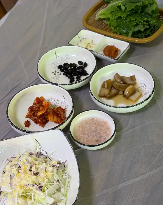 김치, 쌈 채소, 마늘, 쌈장 등이 담긴 여러 개의 접시들