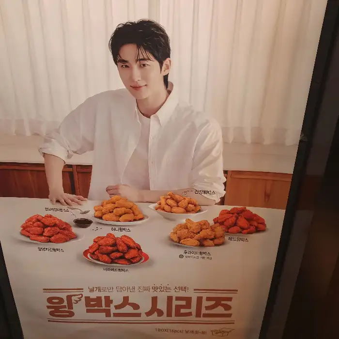 젊은 남성 모델이 여러 종류의 치킨을 배경으로 서 있는 광고판