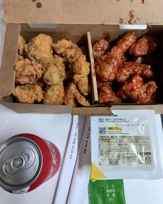 두 칸으로 나뉜 박스에 담긴 후라이드 치킨과 양념 치킨, 그리고 콜라 한 캔