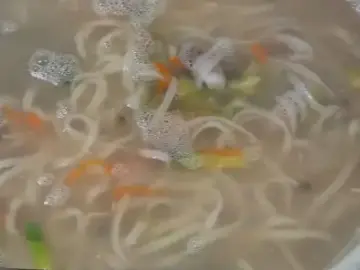 따뜻한 국물의 칼국수가 담긴 큰 그릇과 집게