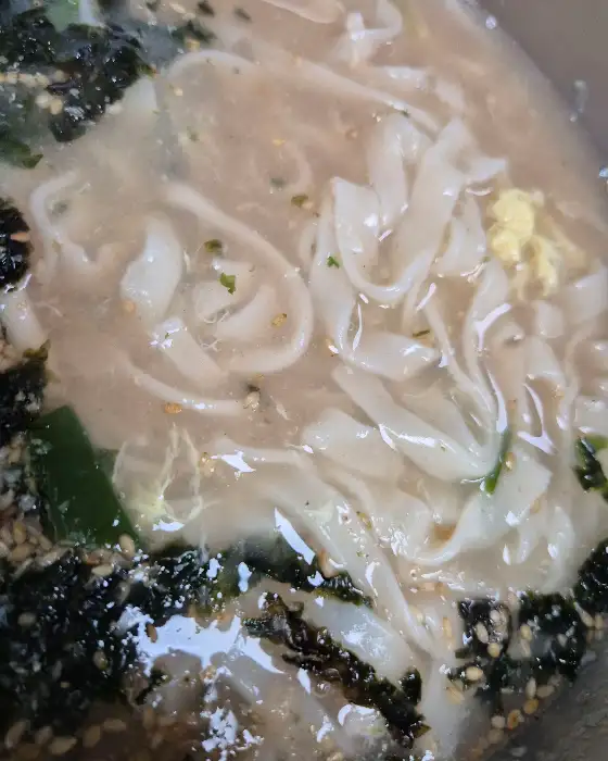 뽀얀 국물에 얇은 면발과 김가루, 깨가 뿌려진 칼국수