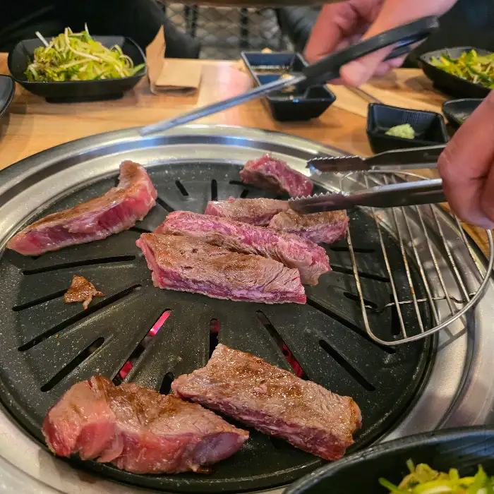 잘 구워진 소고기 한 점을 집는 모습