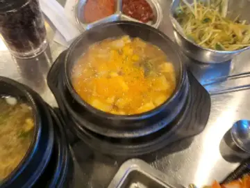 육즙 가득한 찌개와 신선한 곁들임 반찬이 놓인 테이블 풍경