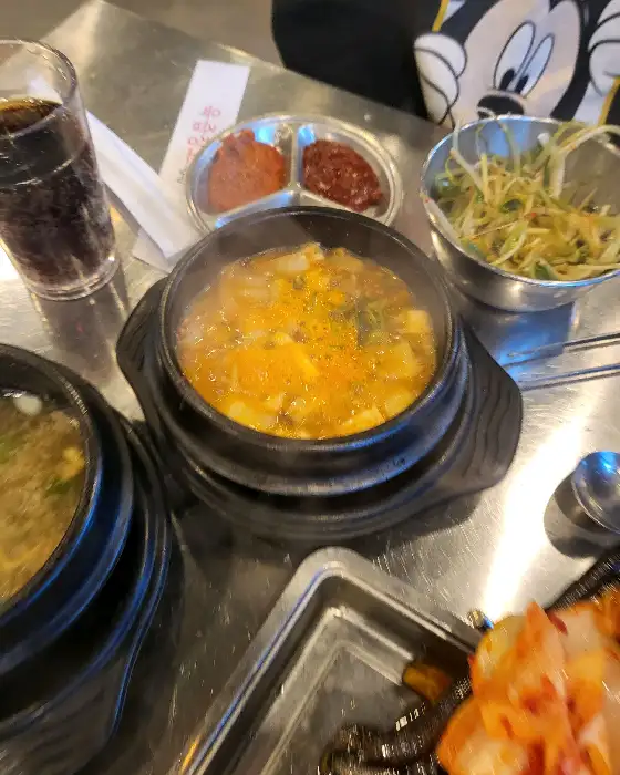 육즙 가득한 찌개와 신선한 곁들임 반찬이 놓인 테이블 풍경