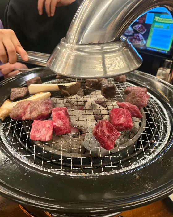 화로 위에서 익어가는 큐브 형태의 소고기와 버섯