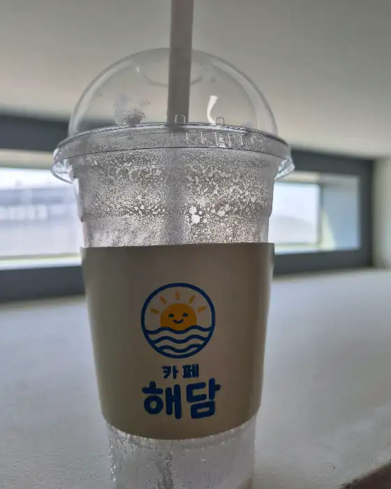 로고가 그려진 컵홀더가 씌워진 투명 컵에 담긴 음료