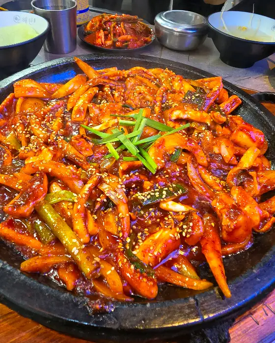 돌판 오징어볶음의 클로즈업 샷, 윤기 나는 양념과 싱싱한 재료