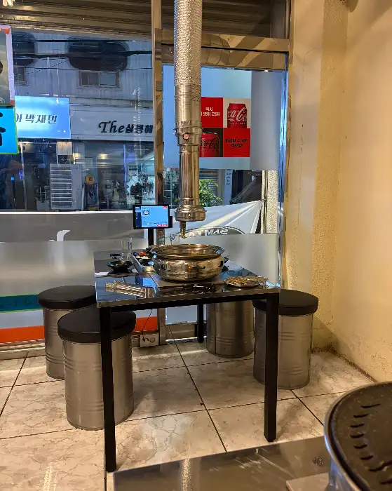 테이블에 놓인 고기를 굽기 위한 불판과 집게