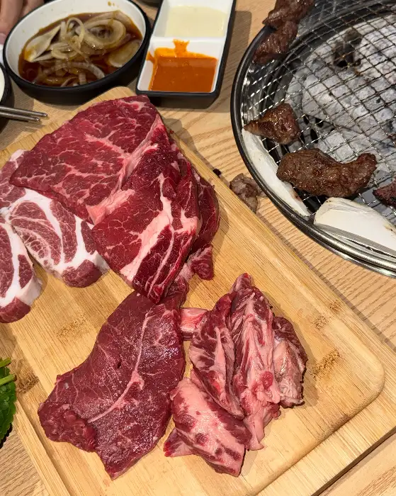 테이블에 준비된 다양한 신선한 고기 부위와 곁들임 찬들