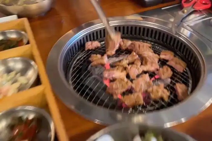 숯불 위에서 익고 있는 돼지갈비와 곁들임 반찬