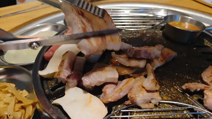집게와 가위로 쟁반집8292 화성향남점의 고기를 자르고 있는 모습
