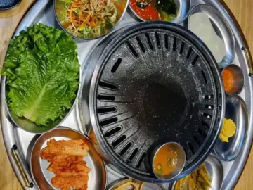 쟁반집8292 화성향남점의 다양한 밑반찬과 신선한 고기가 담긴 쟁반