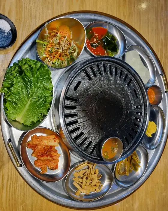 쟁반집8292 화성향남점의 다양한 밑반찬과 신선한 고기가 담긴 쟁반