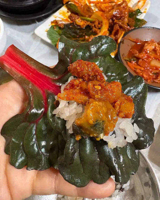 돌솥밥 위에 얹어진 푸짐한 제육과 쌈 채소