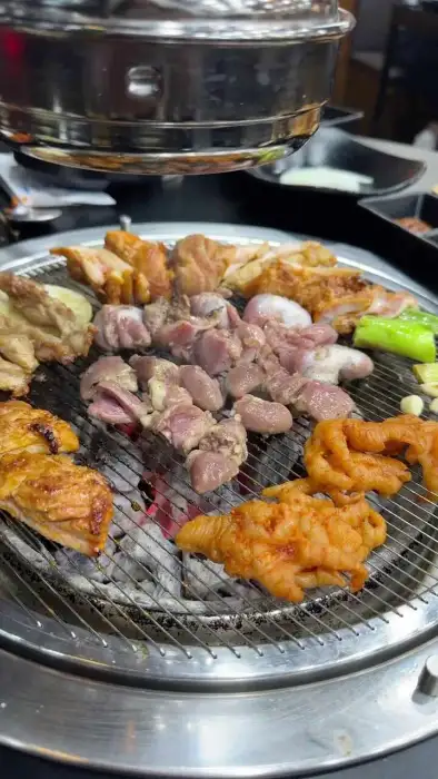 다양한 닭고기 부위와 야채가 숯불 위에서 익어가고 있는 모습
