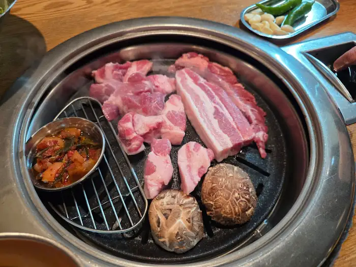 불판 위에 올려진 다양한 고기 종류와 곁들임
