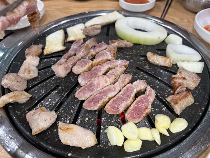 통나무 정육식당의 불판 위에서 구워지는 삼겹살과 곁들임 재료들