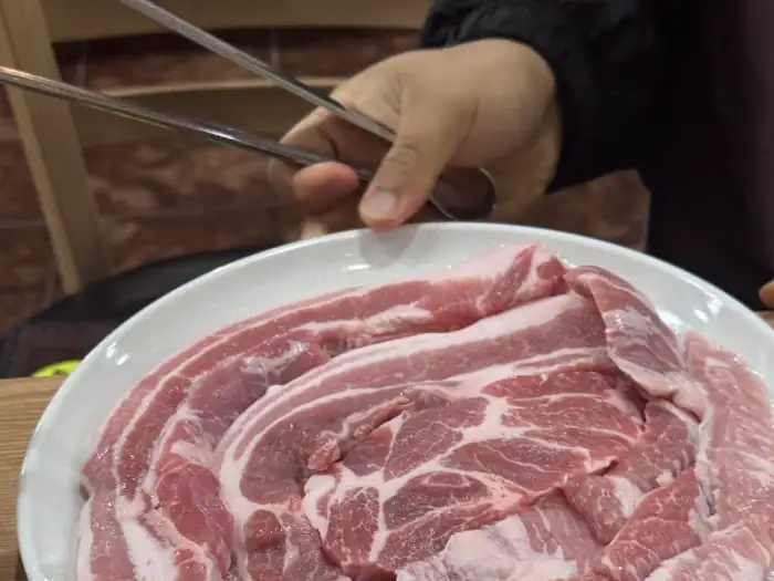 신선한 돼지고기 삼겹살 덩어리가 접시에 담겨 있는 모습