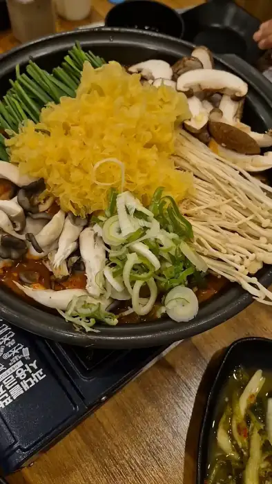 흑염소 전골에 다양한 버섯과 채소가 올라간 모습