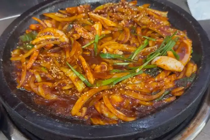 뜨겁게 달궈진 돌판 위에 푸짐하게 담긴 오징어볶음