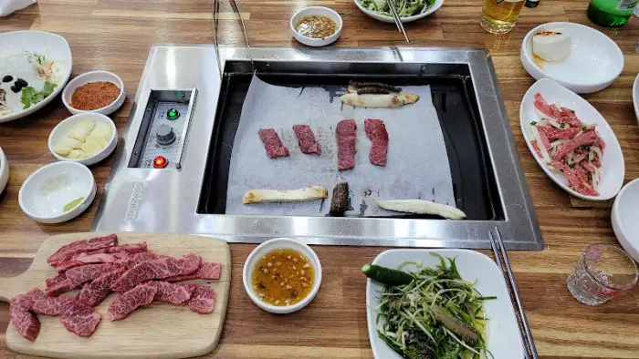 숯불 위에서 구워지는 소고기와 반찬 세팅