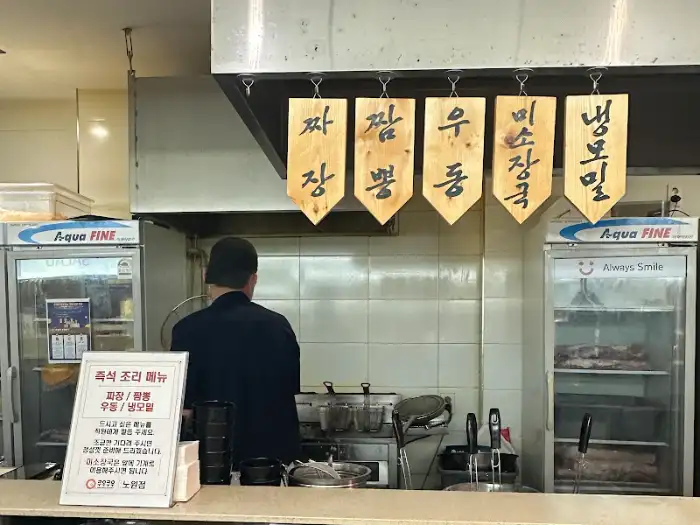주방 앞에서 조리 중인 셰프와 진열된 고기
