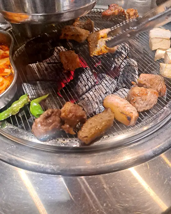 삼목집 철산본점에서 숯불 위에서 맛있게 익어가는 돼지고기