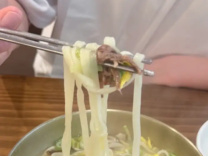 젓가락으로 집어 올린 대종칼국수 수타면과 고기